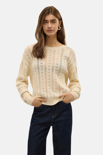 T-shirt écru avec col rond de VERO MODA, doté d'un motif de bretelles ouvert, porté avec un pantalon en cuir noir et des boucles d'oreilles dorées.