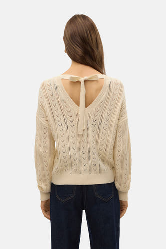 T-shirt écru tricoté avec col rond de VERO MODA, dos en V et détail de côtes, sur un modèle en jeans foncés.