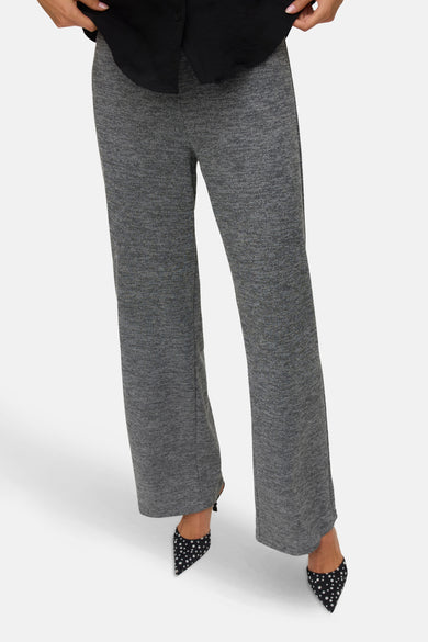 Pantalon gris de VERO MODA, avec une subtile texture et porté avec des escarpins noirs à motifs blancs.