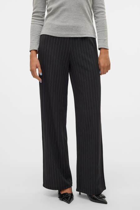 Pantalon noir avec rayure blanche de VERO MODA, associé à une chemise grise et des escarpins noirs.