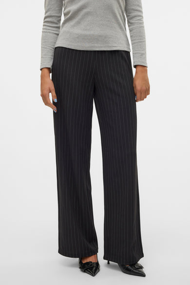 Pantalon noir avec rayure blanche de VERO MODA, associé à une chemise grise et des escarpins noirs.