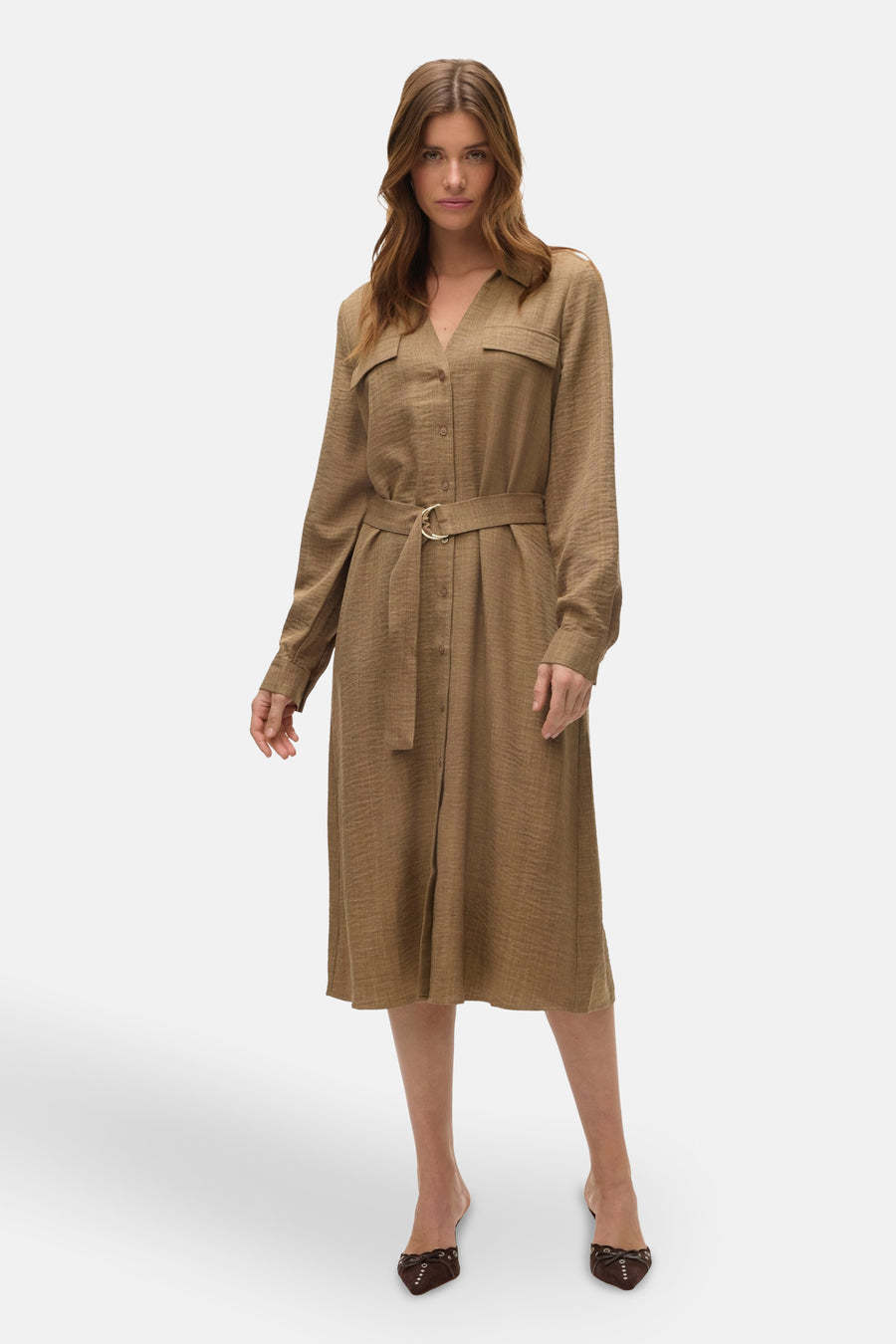 Vrouw in bruine linnen jurk met ceintuur en bruine schoenen, staand.