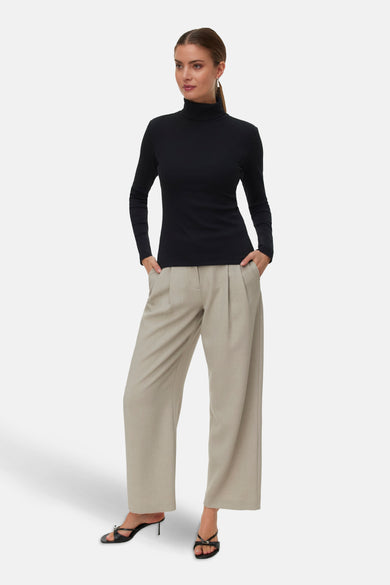 T-shirt noir à manches longues de VERO MODA, porté avec un pantalon beige large et des talons noirs.