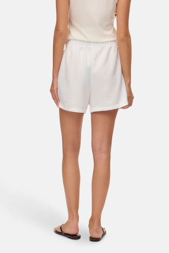 Short blanc de VERO MODA, vu de derrière, avec une ceinture élastique et des sandales.