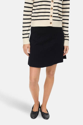 Jupe courte noire de VERO MODA, avec une coupe droite et portée avec un cardigan rayé et des chaussures noires.