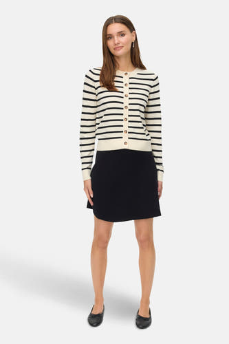 Jupe courte noire de Vero Moda, associée à un gilet rayé tricoté et des ballerinas noires.