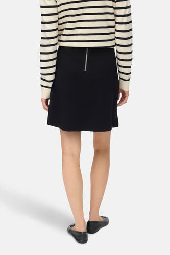 Jupe courte noire de VERO MODA® avec fermeture éclair argentée à l'arrière, portée avec un pull rayé.