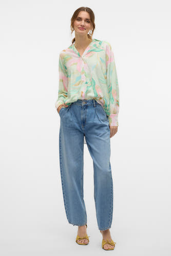 Jean special fit de denim bleu de VERO MODA, avec des plis et porté avec une blouse imprimée.