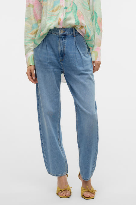 Jean special fit de denim bleu de VERO MODA, avec des plis à l'avant, associé à une robe imprimée.