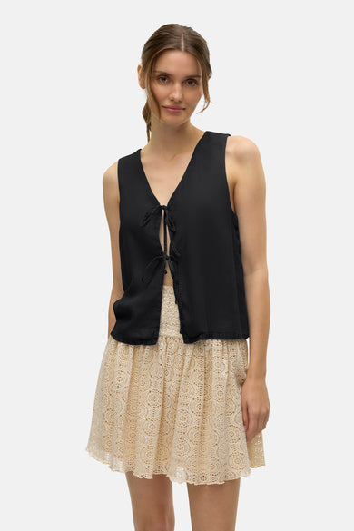 Blouse noire de VERO MODA avec une devanture plissée et une jupe en dentelle beige.