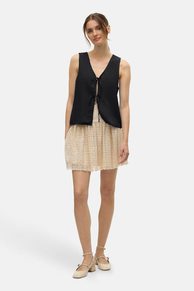 Zwarte blouse van VERO MODA met een openvallende voorkant en een beige kanten rok.
