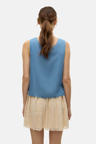 Blouse bleue de VERO MODA, avec une légère texture et portée avec une jupe tricotée.