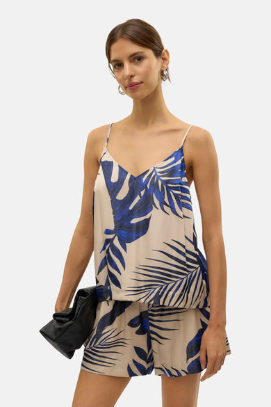 Blouse sans manches bleue de VERO MODA®, à imprimé feuille, associée à une pochette noire et des sandales compensées noires.