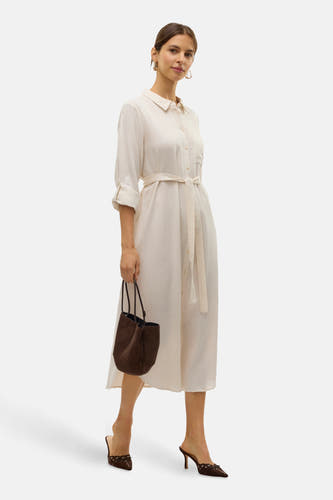 Manteau beige à longues manches de VERO MODA®, avec une ceinture et un sac brun et des bottes.