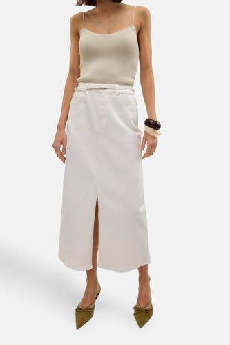 Robe longue blanche de Vero Moda, avec une fente à l'avant, portée avec un haut et des bottes.
