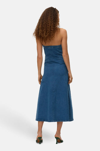 Denim strapless jurk, achterkant, krullend haar, groene hakken.
