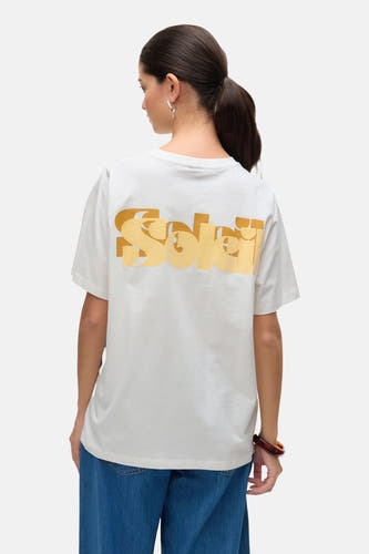 T-shirt blanc de VERO MODA, avec des manches courtes et une impression jaune vive sur l'arrière, associé à des jeans bleus.