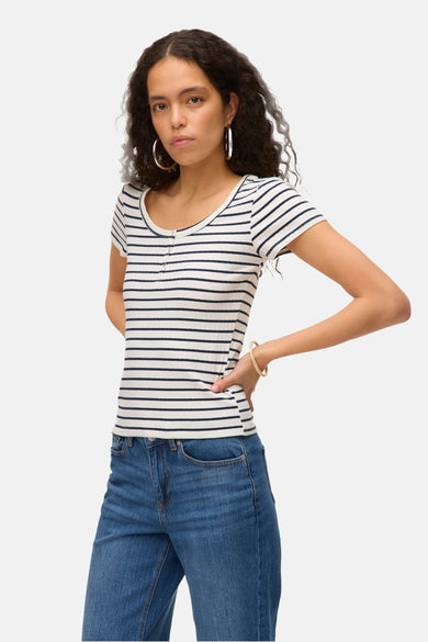 T-shirt rayé blanc à manches courtes de VERO MODA, avec des détails de boutons et associé à des jeans et des boucles d'oreilles en or.