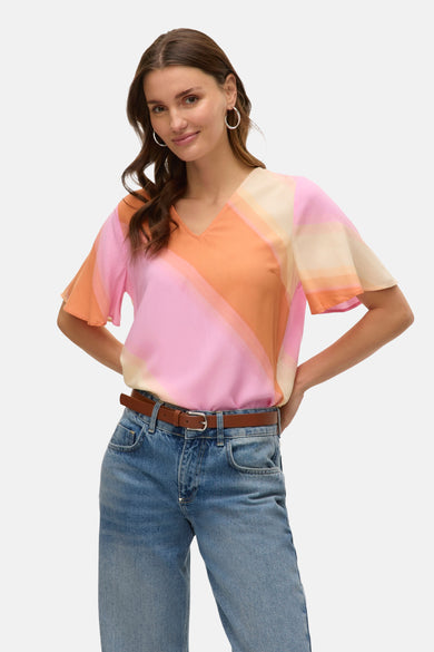 Blouse multicolore de VERO MODA, avec une transition de couleur diagonale et portée avec un ceinture marron et des jeans bleus.