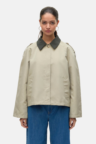 Blazer écru de VERO MODA avec col vert foncé et jeans bleu visible.