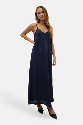 Vrouw draagt een marineblauwe maxi-jurk met spaghettibandjes.