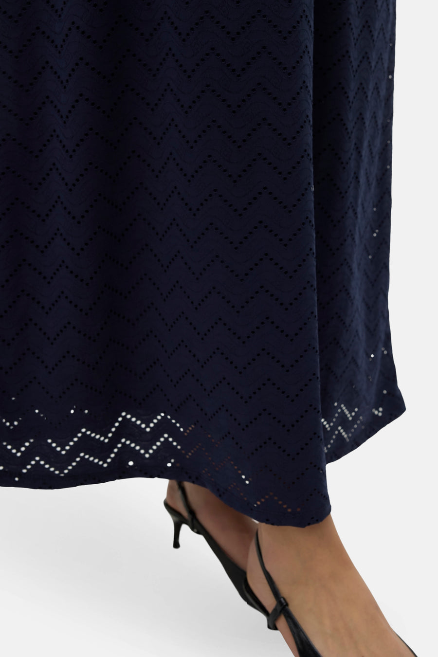 Marineblauwe jurk met ajourpatroon, slingback hakken.