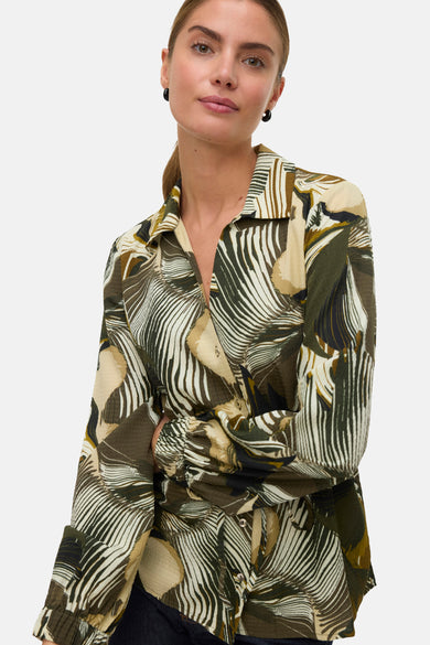 Chemise verte à manches longues de VERO MODA, avec motif de feuille et boucles d'oreilles noires.
