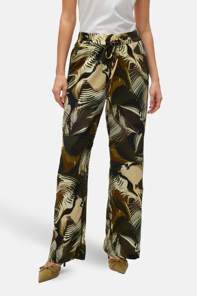 Pantalon vert de VERO MODA avec imprimé feuilles, associé à des escarpins beige avec une lanière.