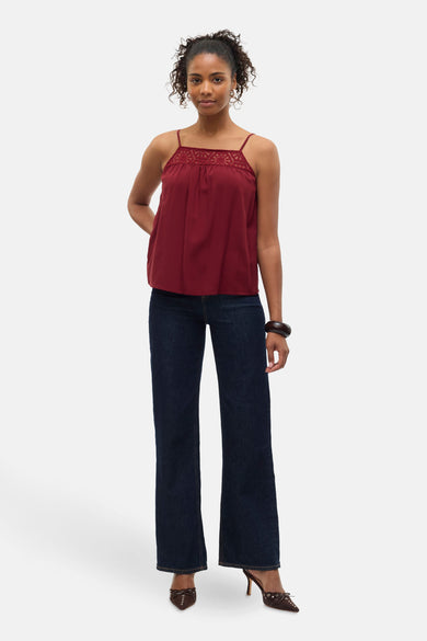 Blouse sans manches bordeaux de Vero Moda, avec des détails bordés et associée à des jeans noirs et des bottes marrons.