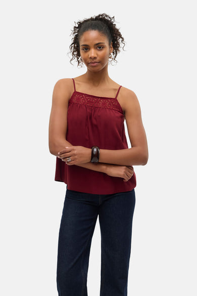 Blouse sans manches bordeaux de Vero Moda, finie avec des détails en biais sur le devant, associée à des jeans foncés et un bracelet.