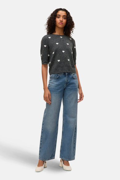 Sweat-shirt gris à col rond de VERO MODA®, orné de cœurs blancs et associé à des jeans larges et des baskets légères.