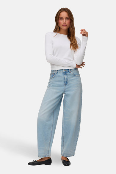 Jean en denim bleu clair de VERO MODA, à jambes larges, combiné avec une chemise blanche et des ballerines noires.