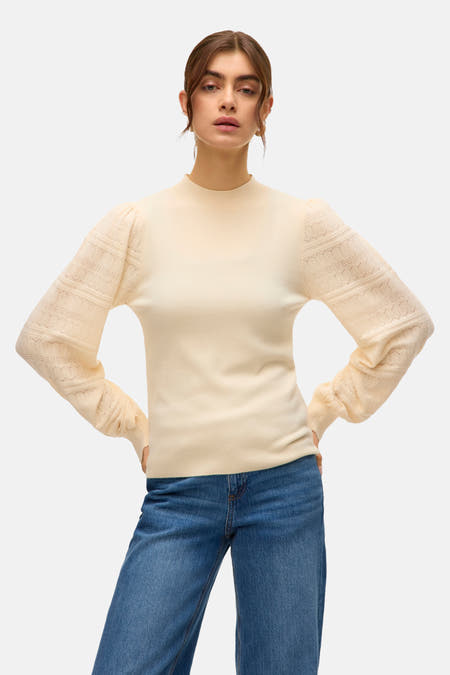 T-shirt écru avec col rond de VERO MODA, avec des manches longues détaillées et associé à des jeans bleus.