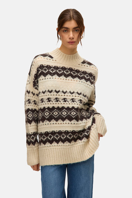 Sweat-shirt écru avec col rond de VERO MODA, motif fair isle marron foncé et manches longues, associé à un jean bleu.