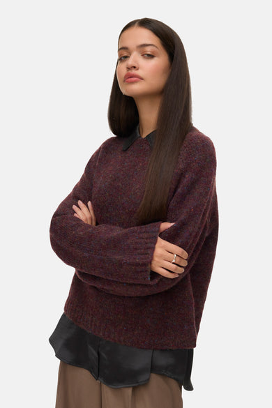Pull Bordeaux avec col rond de VERO MODA®, porté avec une blouse noire et un pantalon marron.