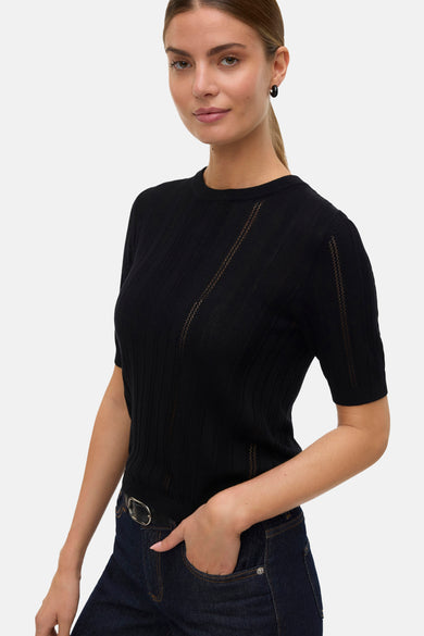 Sweat-shirt noir à col rond de VERO MODA, avec des rayures subtiles et un jean avec ceinture.