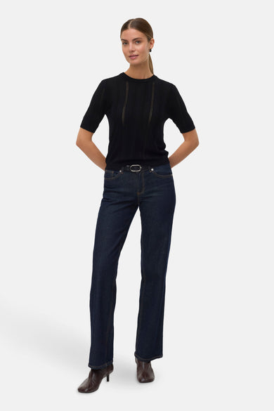 Pull noir avec col rond de VERO MODA, doté de rayures ajourées verticales, associé à un jeans foncé et des bottes.