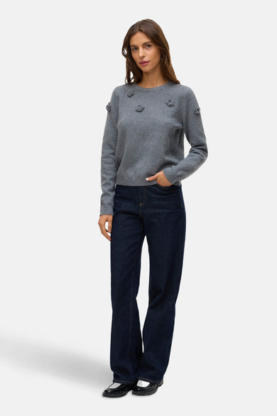 Sweat-shirt gris avec col rond de Vero Moda, terminé avec des détails floraux, associé à un jeans bleu marine et des chaussures noires.