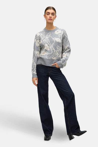 Sweat-shirt gris à col rond de VERO MODA, avec un imprimé floral, associé à des jeans foncés et des chaussures noires.