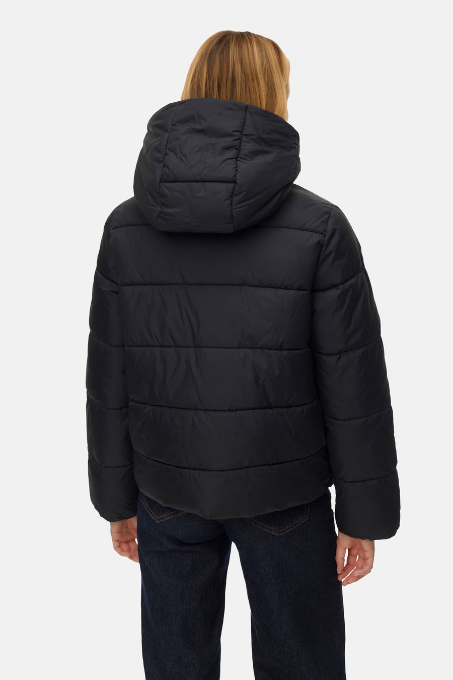 Manteau court noir de Vero Moda, avec capuche, vu de derrière, porté sur un pantalon de travail foncé.