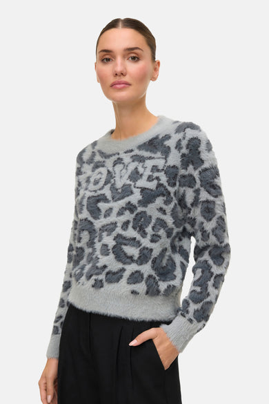 Sweat-shirt gris à col rond de VERO MODA, doté d'un imprimé léopard avec une étiquette 'LOVE', associé à un pantalon noir.