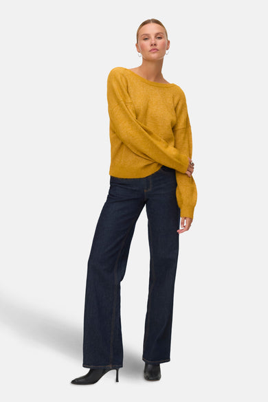 Sweat-shirt VERO MODA avec col rond, porté avec des jeans foncés et des bottes noires à talon.