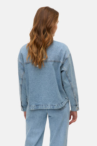 Lichtblauwe denim jas van Vero Moda, gezien van achteren, met golvend bruin haar.
