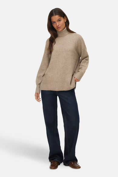 Beige rolkraagtrui van VERO MODA®, met lange mouwen, gecombineerd met een donkere jeans en bruine schoenen.

