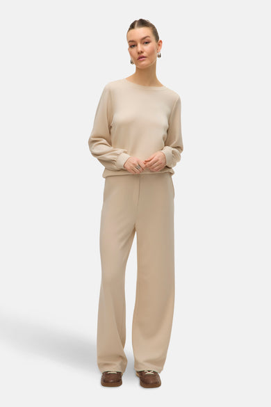 Jean écru de VERO MODA, avec des jambes larges, porté avec un haut coordonné et des chaussures marrons.