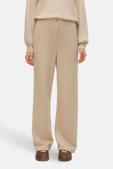 Pantalon écru de VERO MODA, avec une fermeture à boutons et des jambes larges, associé à des chaussures marron.