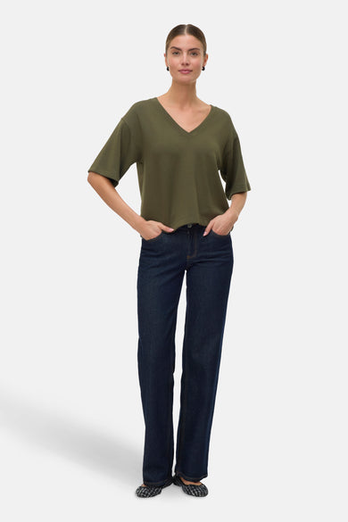 T-shirt vert avec manches courtes de VERO MODA®, porté avec des jeans foncés et des chaussures plates.