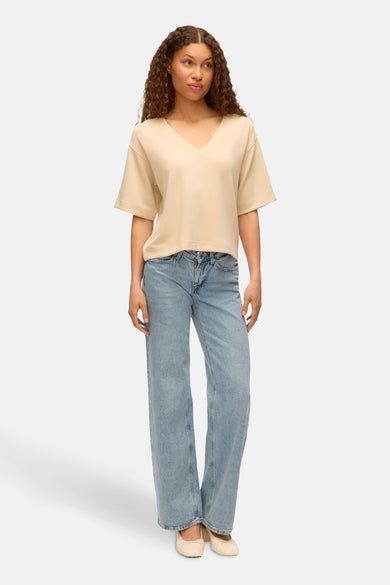T-shirt écru à manches courtes de VERO MODA, porté avec des jeans larges et des ballerines.