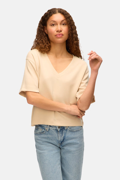 T-shirt écru à manches courtes de VERO MODA, associé à un jean bleu.