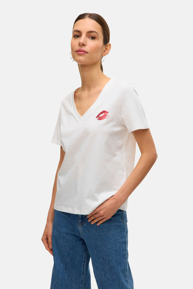 T-shirt blanc à manches courtes de VERO MODA, avec une impression de baiser rouge et porté avec des jeans bleus.